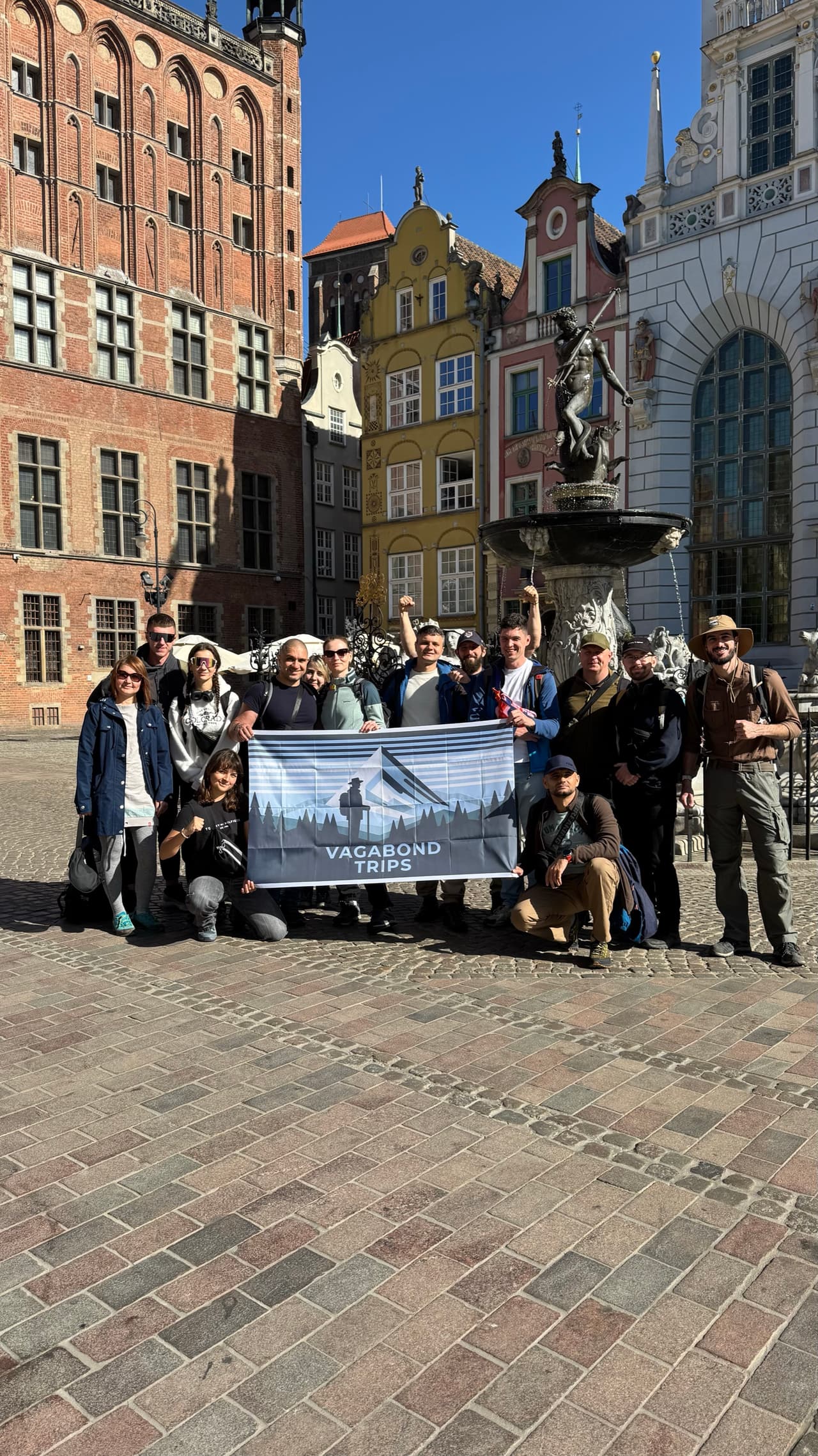 Участники с флагом Vagabond Trips перед историческими фасадами Гданьска